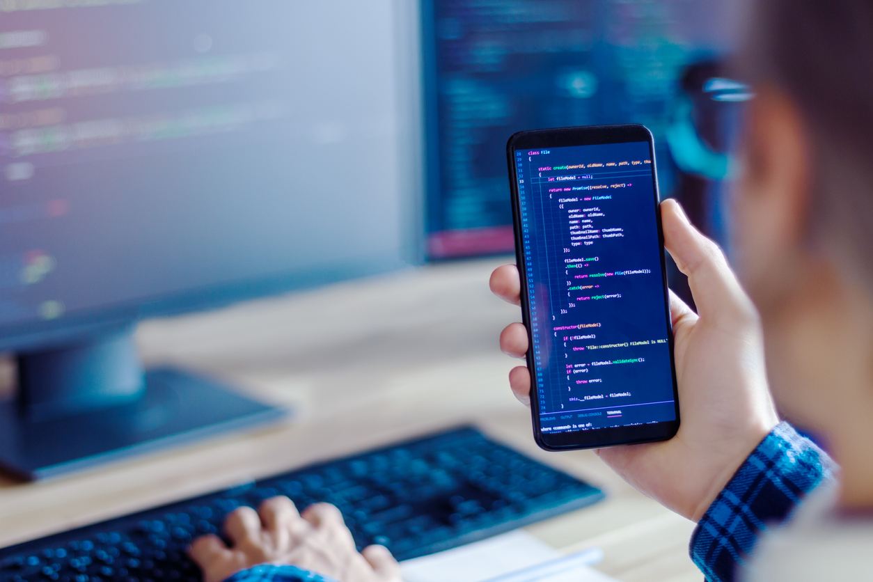 Programmer making a software using a mobile phone and computer